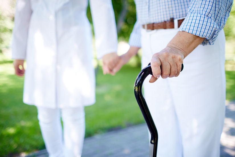 A caregiver with a resident using an offset handle cane.