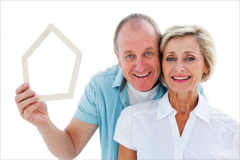 Happy senior couple holding a house outline